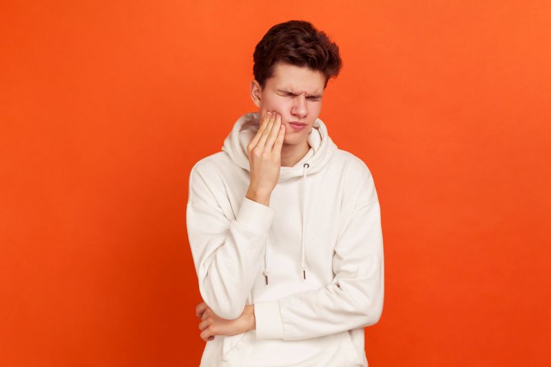 Young man holding his jaw in pain due to bruxism and teeth grinding