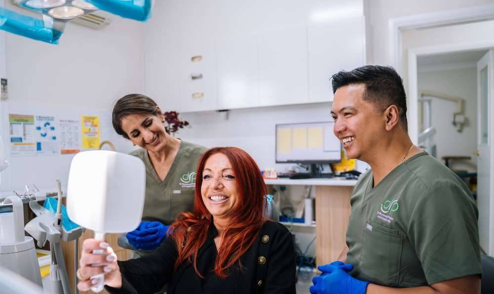 Dr Raymond Platon and dental team with a smiling patient at Dr Raymond Platon & Associates in Wetherill Park.
