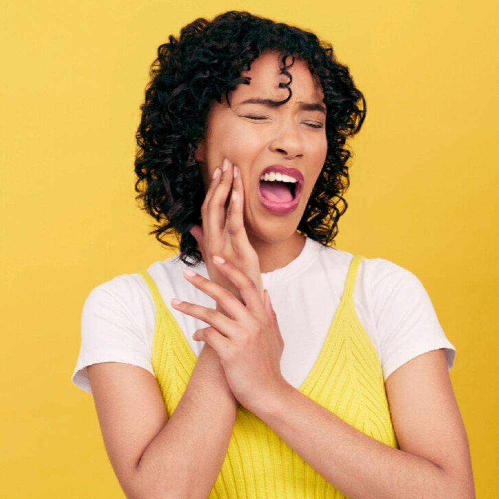 Woman holding her jaw in pain – dental pain relief.