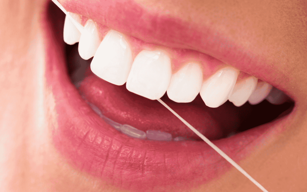 Floss removing food stuck between teeth to help maintain healthy gums