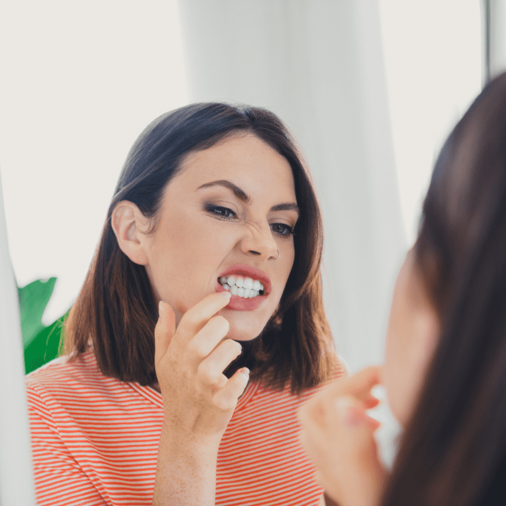 Woman checking bleeding gums in mirror concerned about gum health in Wetherill Park