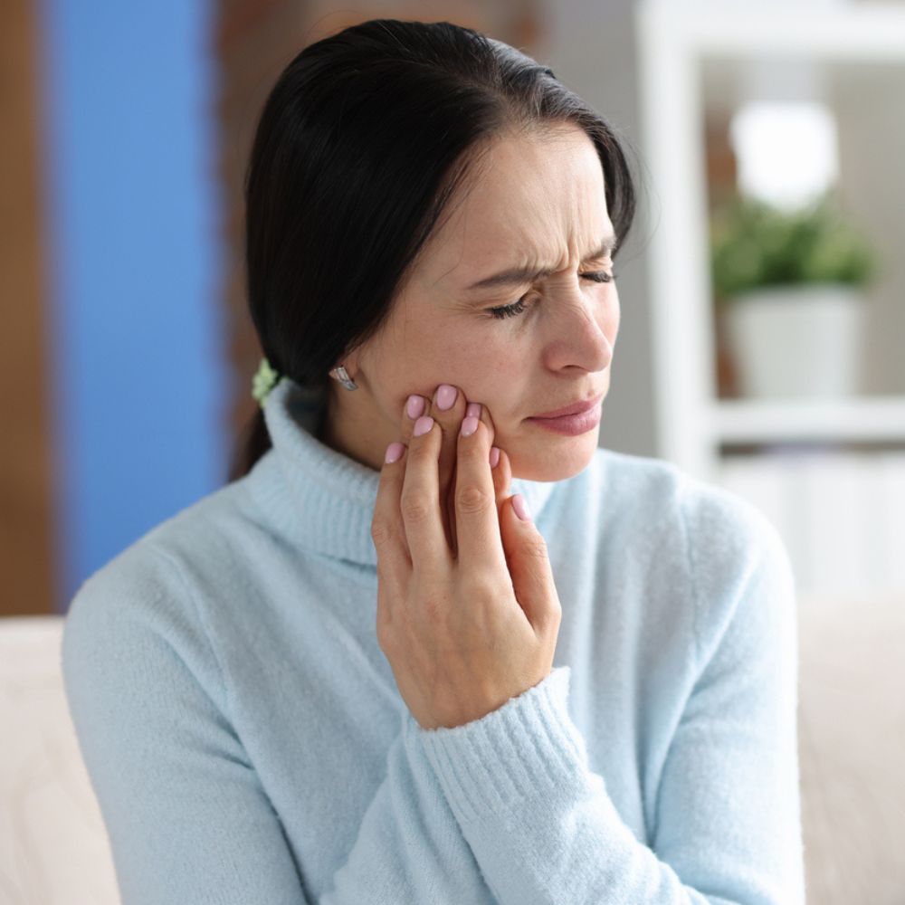 Woman experiencing tooth infection pain holding cheek in Wetherill Park