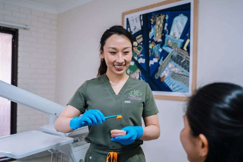 Oral Health Therapist Caroline Nguyen demonstrating how to care for a dental crown during a patient consultation in Wetherill Park.