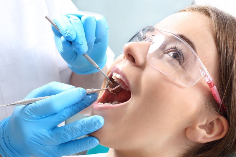 Dentist assessing a damaged dental crown to determine whether it can be repaired or replaced in Wetherill Park.