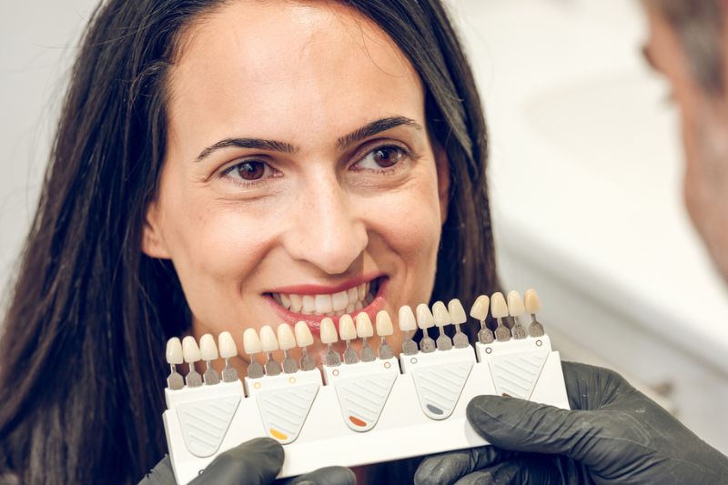 Dentist comparing a patient's tooth shade before professional teeth whitening in Wetherill Park.