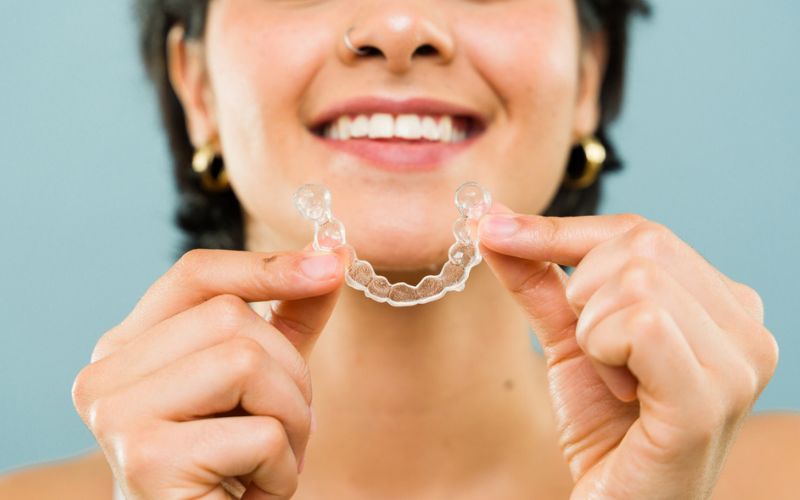 Patient holding a clear orthodontic retainer after braces treatment